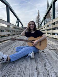 学生诗人汉娜·卡米洛坐在桥上弹吉他